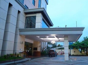 A modern building with a covered entrance, a car parked in front, and a well-maintained garden area. - Grand Victoria Samarinda (Samarinda)