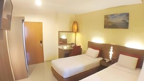 Habitación de hotel con dos camas, un baño, un cuadro en la pared y una puerta que da a otra habitación.