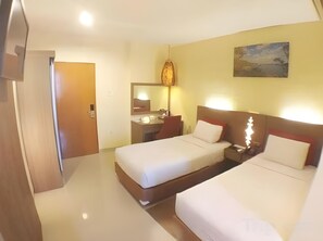 A hotel room with two beds, a bathroom, a painting on the wall, and a door leading to another room. - Amans (Ambon)
