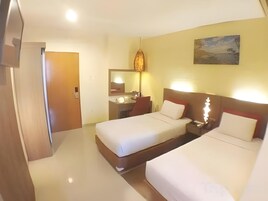 Habitación de hotel con dos camas, un baño, un cuadro en la pared y una puerta que da a otra habitación.