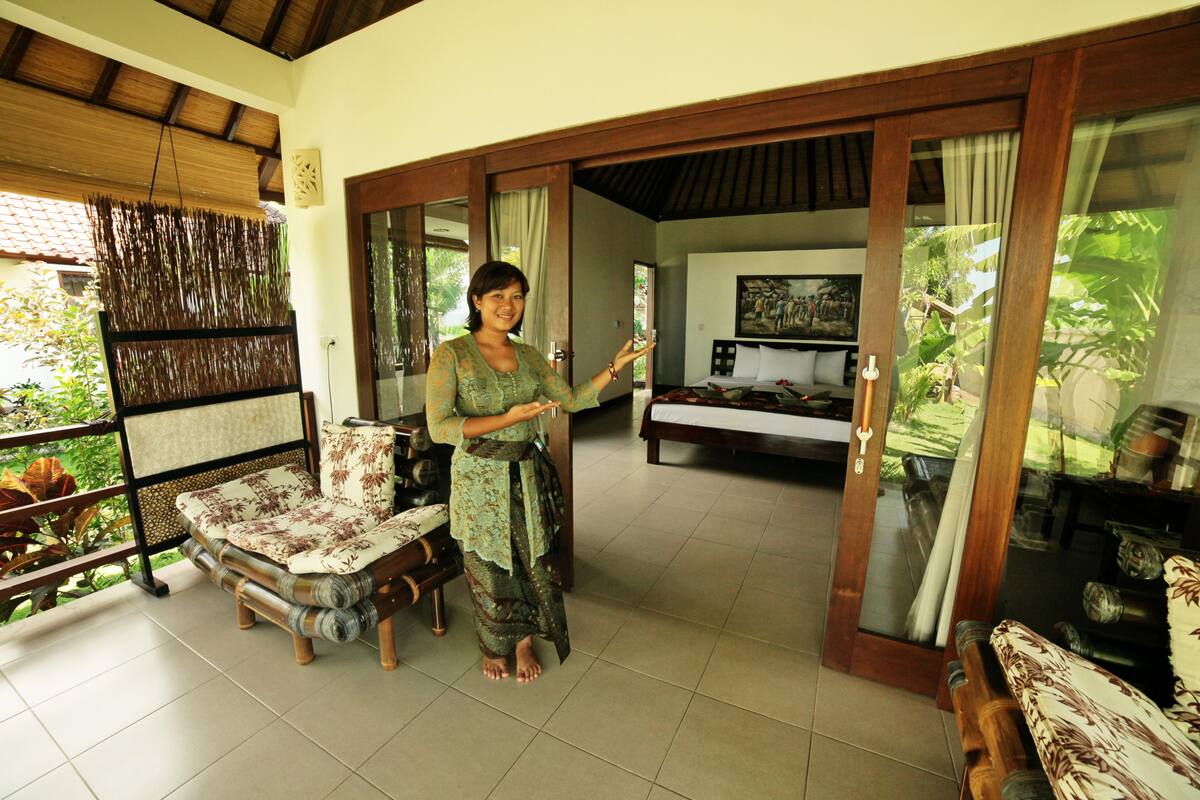 A room with a wooden ceiling, a sofa, a chair, and a bed.