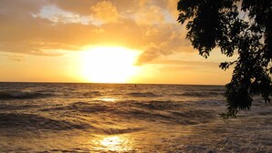 A sunset over the ocean with waves reflecting the sun's light. - Bali Dream House (Karangasem)