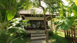 A two-story building with a tiled roof, surrounded by lush greenery and banana plants. - Bali Dream House (Karangasem)