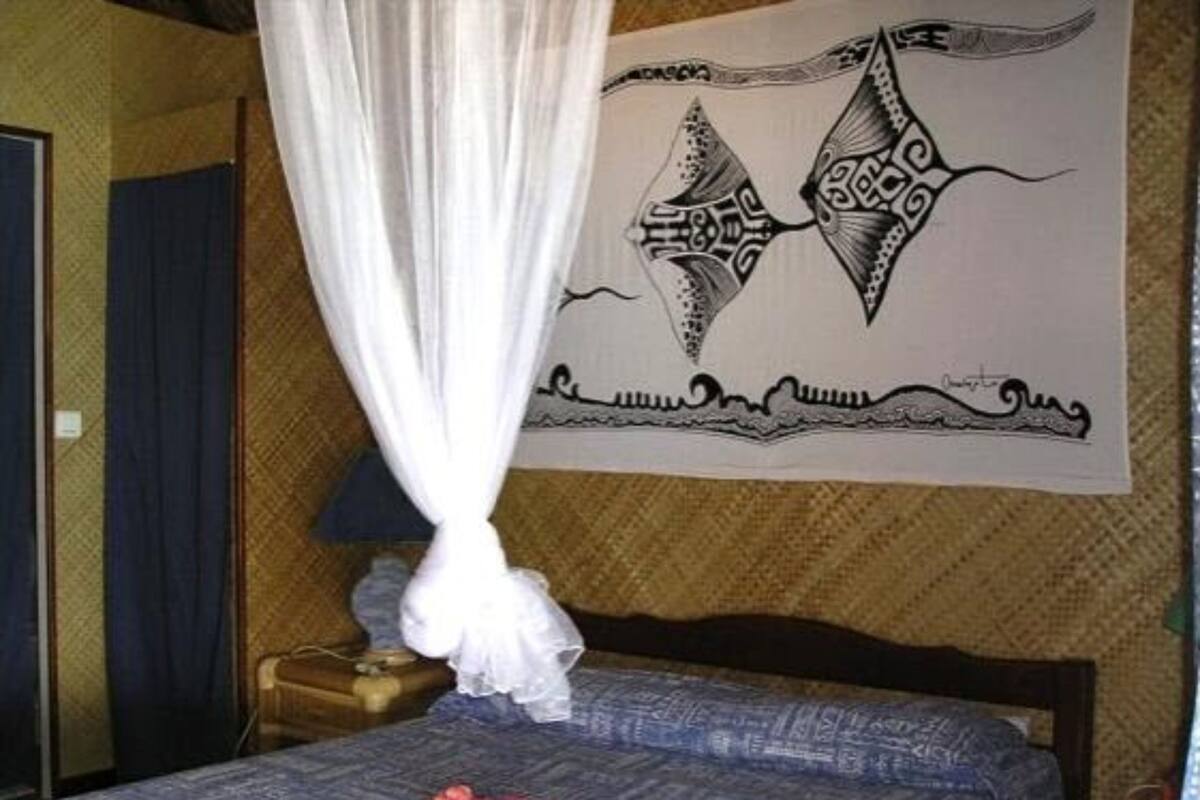 A bedroom with a bed, a mosquito net, and a wall tapestry.