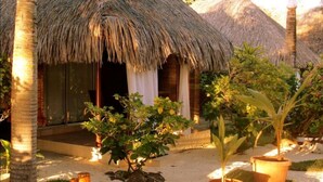 A thatched-roof structure with a covered entrance, surrounded by palm trees and potted plants. - Village Temanuata (Bora Bora)