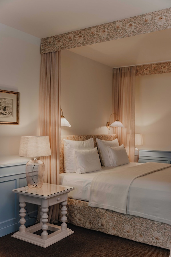 A hotel room with a bed, two bedside tables, a nightstand, a lamp, and a framed picture on the wall. - König von Ungarn (Vienna)