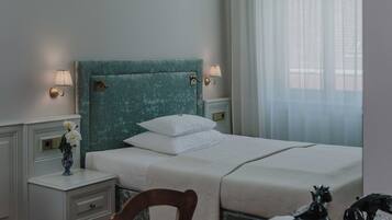 A neatly made bed with white linens, a teal headboard, and two bedside lamps.