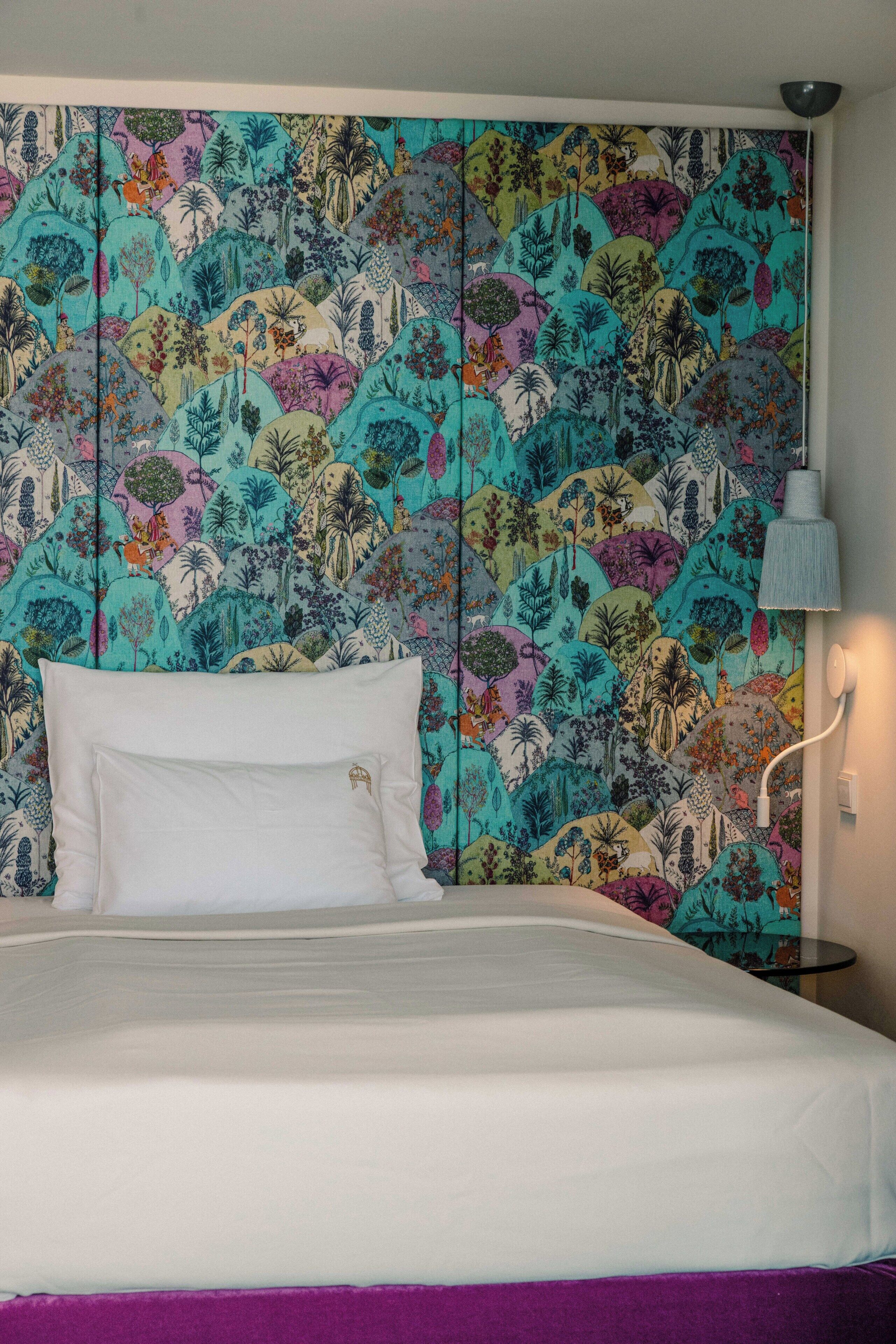Een bed met witte lakens en een paars accent aan het voeteneind.
