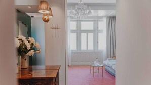 A bedroom with a large window, a chandelier, a bedside table, and a bed. - König von Ungarn (Vienna)