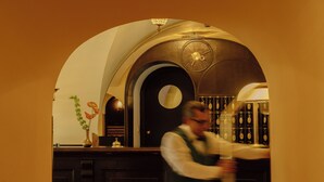 A bar area with a counter, a clock, and a wine rack. - König von Ungarn (Vienna)