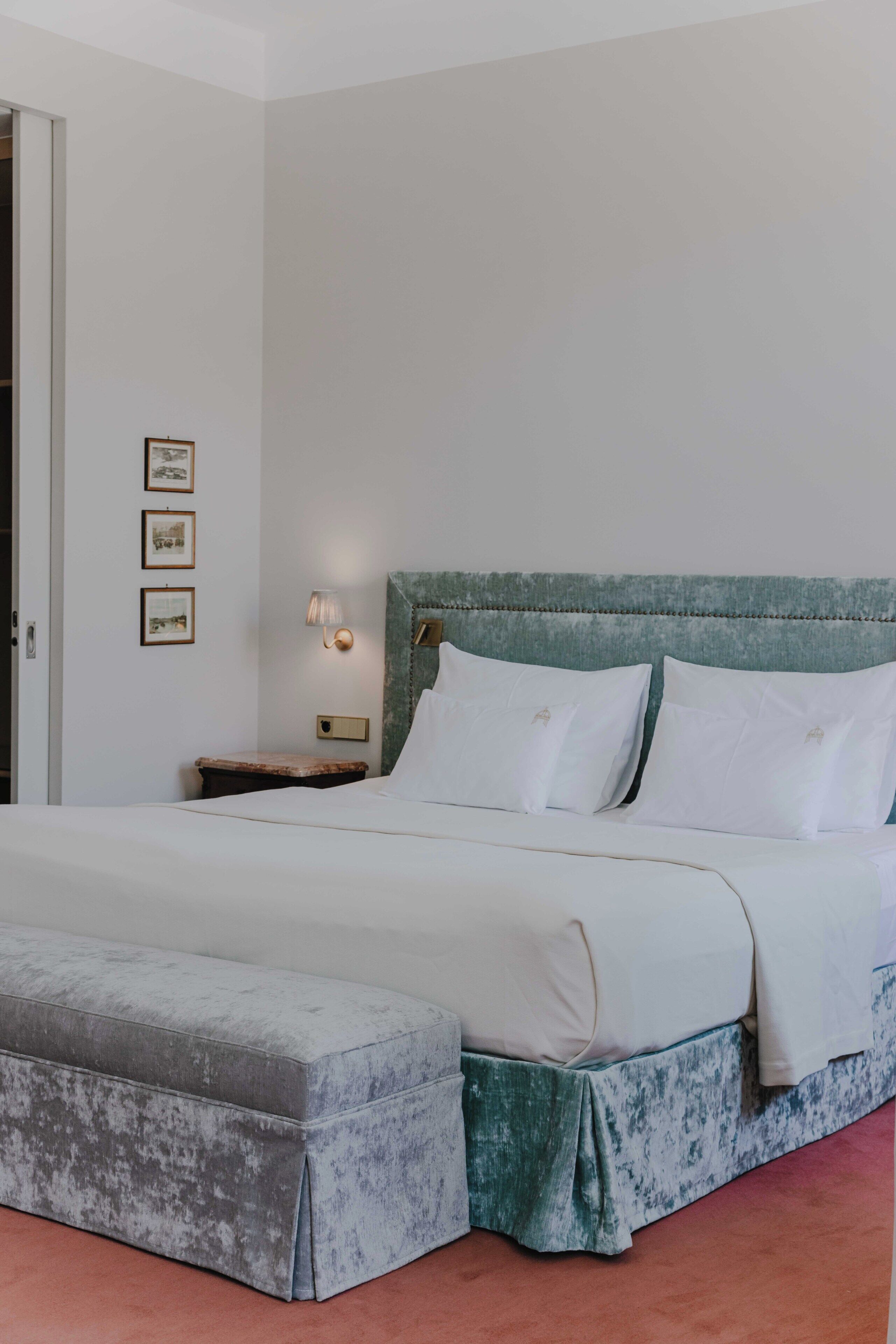 Ein Schlafzimmer mit Bett, Nachttisch, Lampe und Bildern an der Wand.
