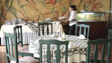 A dining area with round tables, chairs, and a wall with abstract art.