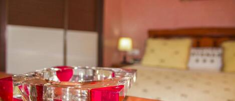 A hotel room with a bed, a nightstand, and a table with a decorative glass object.