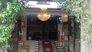 A lobby with a red carpet, a chandelier, and potted plants. - Atenas Hotel (Tetouan)