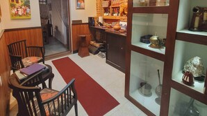 A cozy room with a wooden dining table, chairs, a red rug, and a bookshelf filled with books and decorative items.