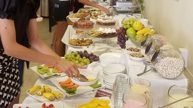 A buffet setup with various food items and a television in the background.
