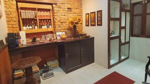 A cozy room with a brick wall, a wooden shelf with bottles, a desk with a keyboard, and a red carpet.