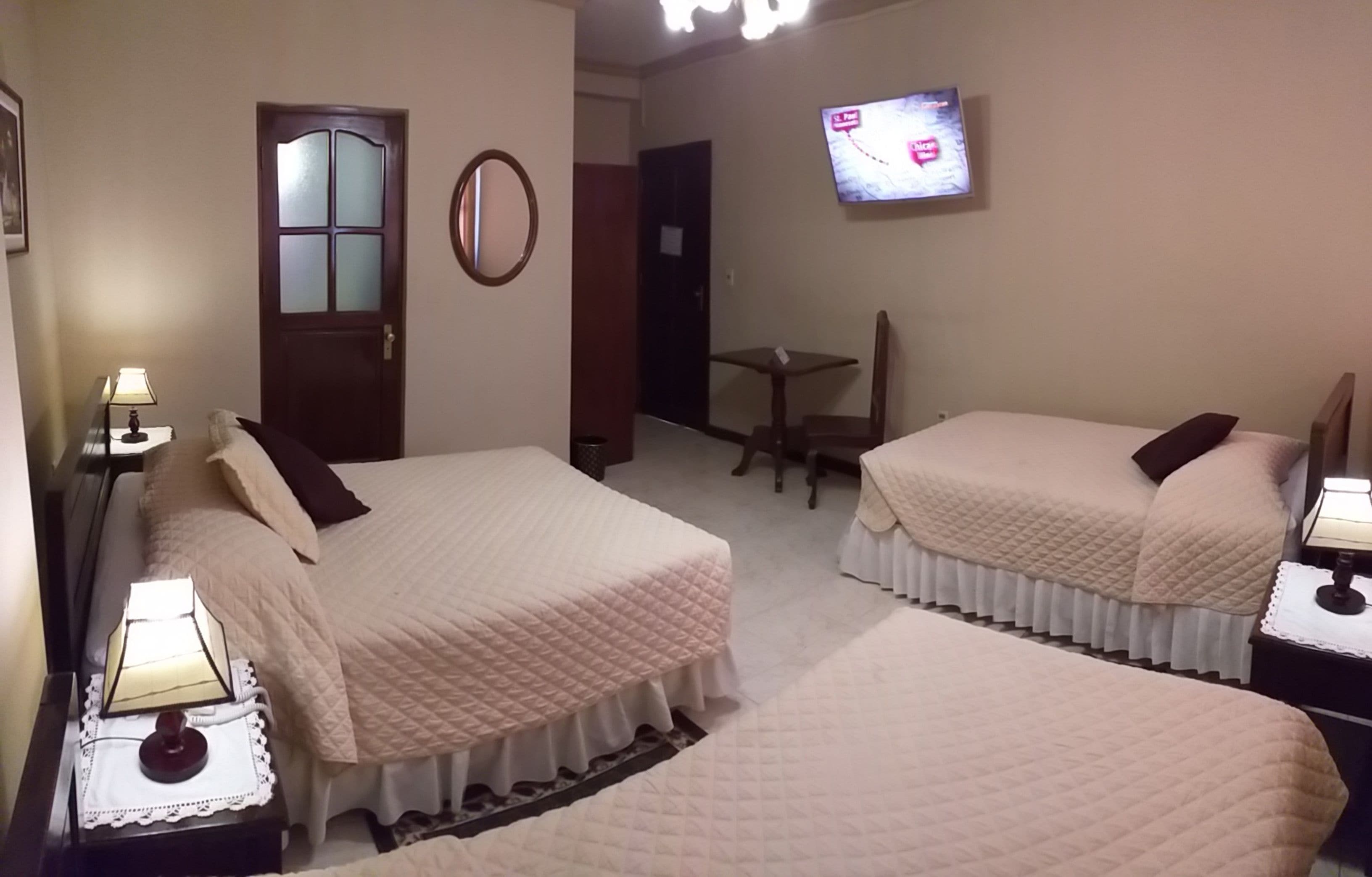 A hotel room with two beds, a television, a small table, and a chair.