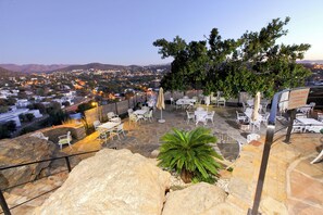 Una terraza con mesas al aire libre, vistas a un pueblo y un cartel sobre el uso de las instalaciones.