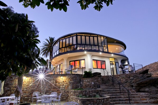 Un edificio moderno de varios niveles con terraza al aire libre y una escalera de piedra.