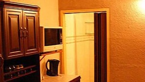 A kitchen with wooden cabinets, a microwave, and a coffee maker. - All Are Welcome (Brakpan)