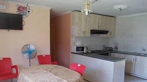 A compact kitchen with a dining area, featuring a microwave, kettle, and a small island. - All Are Welcome (Brakpan)