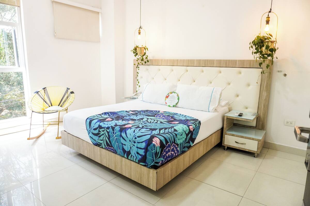 A bedroom with a bed, bedside tables, a chair, and a window.