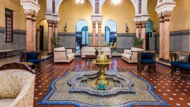 Eine geräumige Lobby mit hohen Bögen, aufwendigen Säulen und einer verzierten Zierbrunnen in der Mitte.