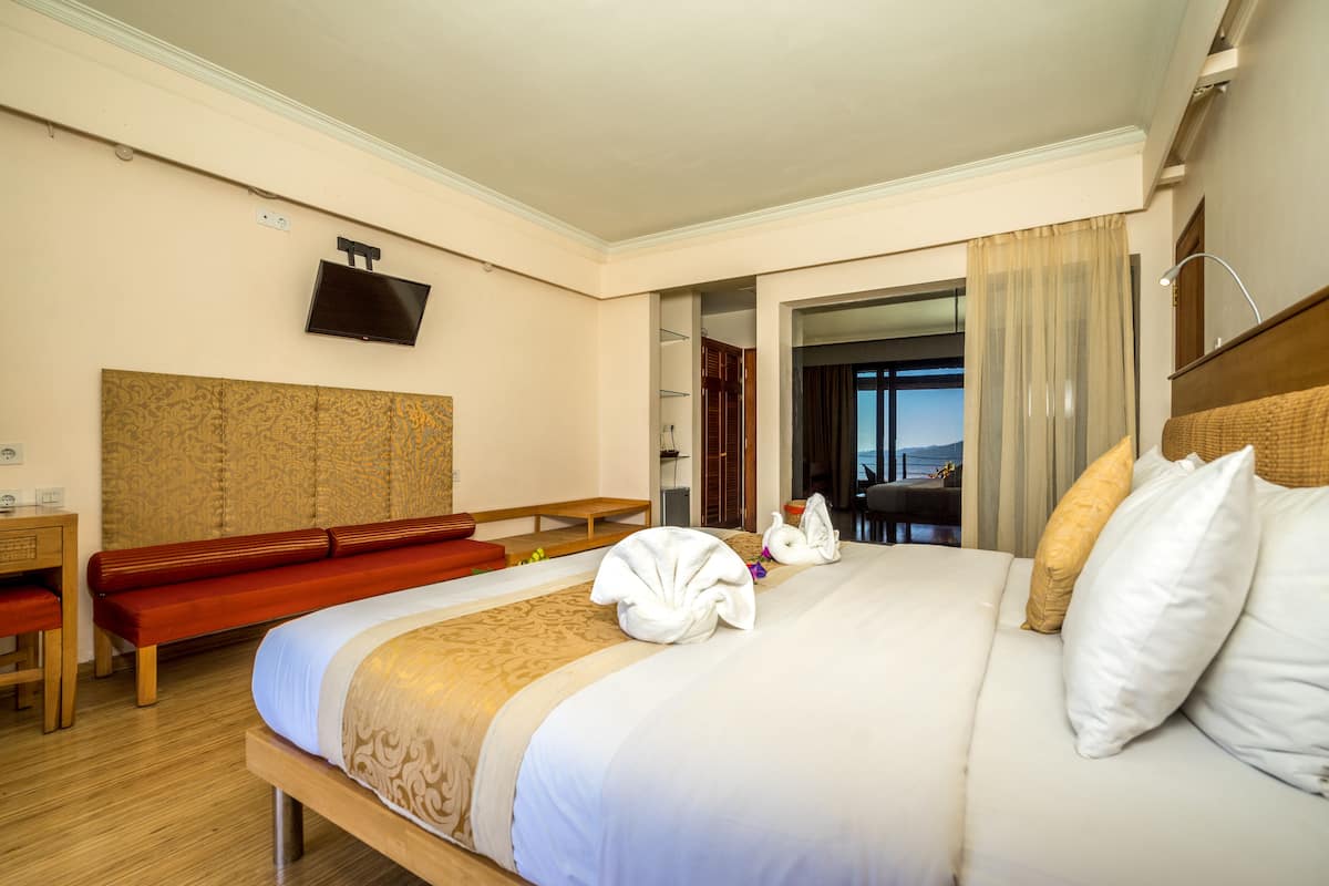 A hotel room with a large bed, a desk, a TV, and a view of the outdoors.