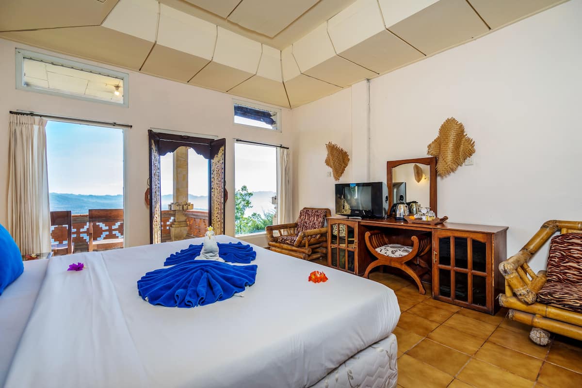 A hotel room with a bed, a desk, a chair, and a view of the ocean.