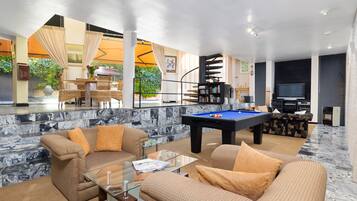 A modern living room with a pool table, comfortable seating, and a television.
