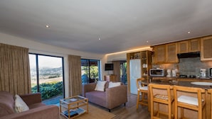 A modern living room with a sofa and armchair, a coffee table, and a view of the outdoors. - Constantia Vista (Cape Town)