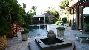 A pool area with a stone fire pit, seating, and lush greenery. - Constantia Vista (Cape Town)