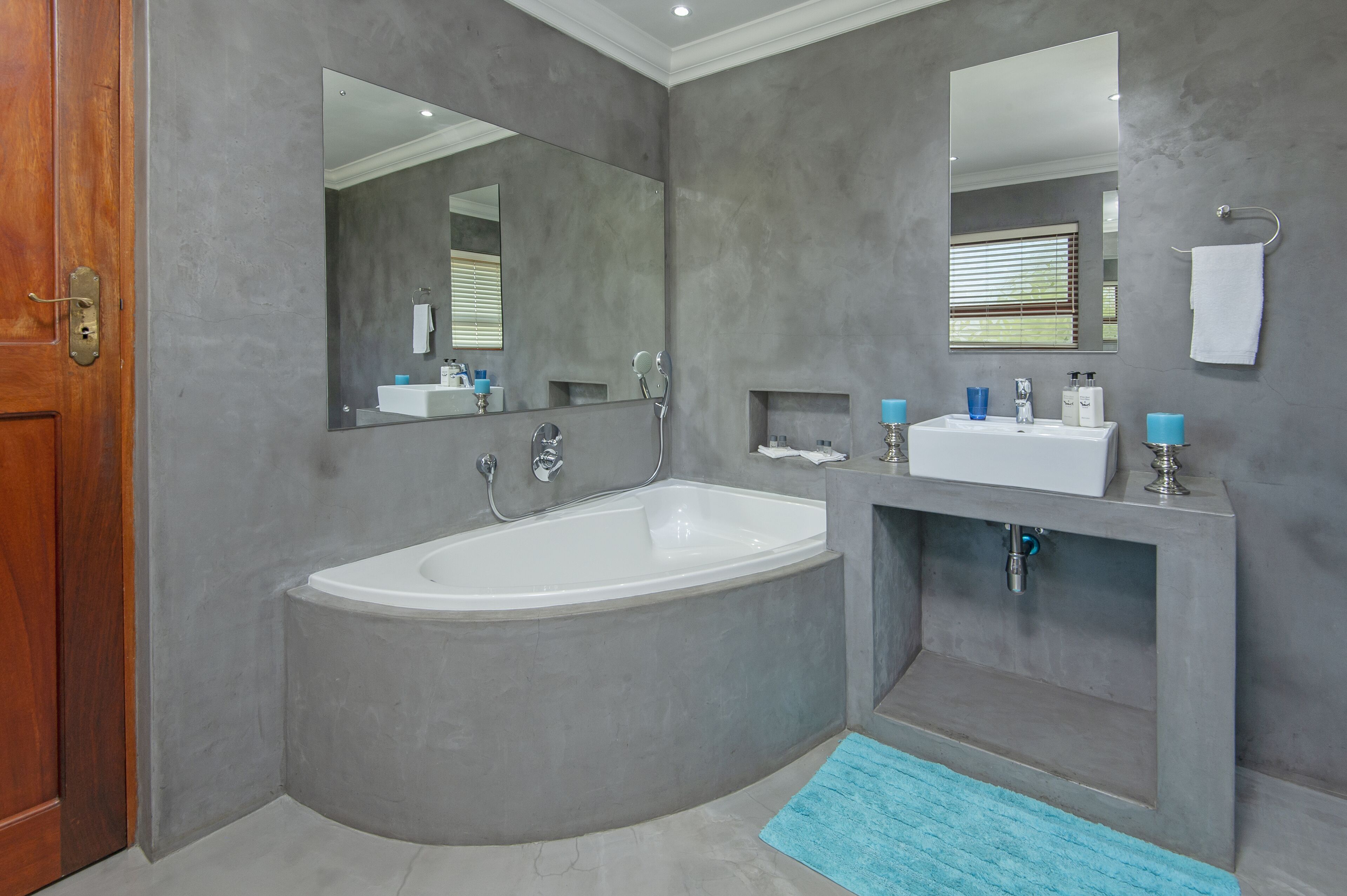 A modern bathroom with a large bathtub, two sinks, and a mirror.