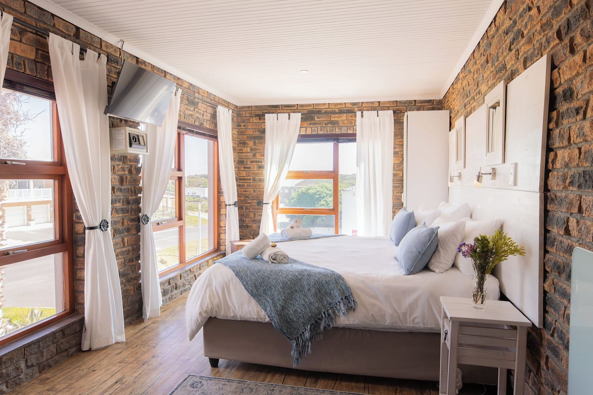 A bedroom with a large bed, a bedside table, and a window with curtains.