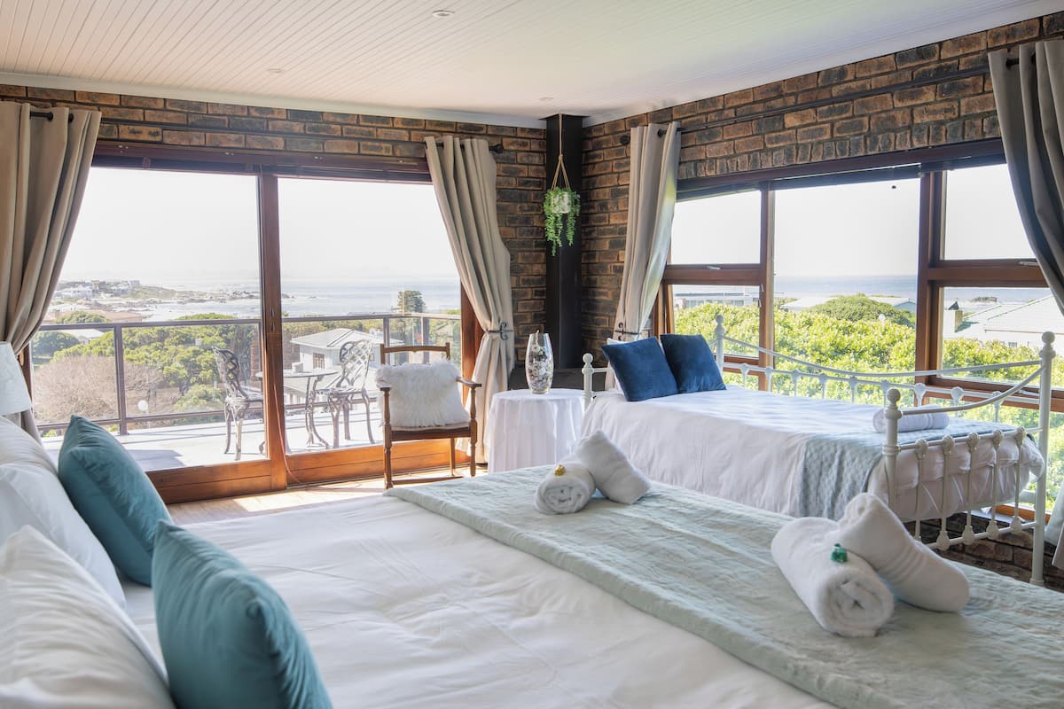 A hotel room with two beds, a view of the ocean, and a balcony with outdoor furniture.