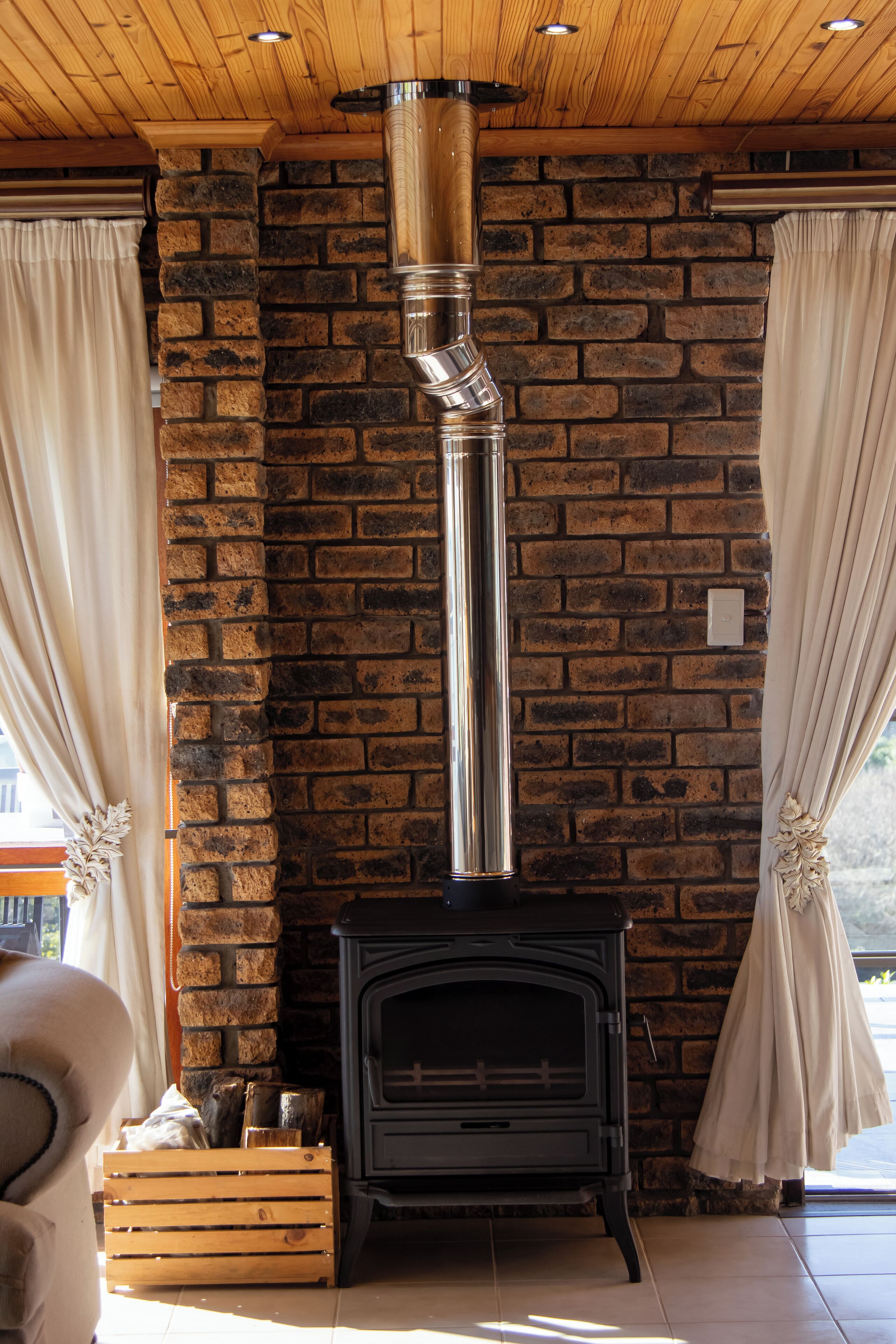 A stone wall with a fireplace and curtains.