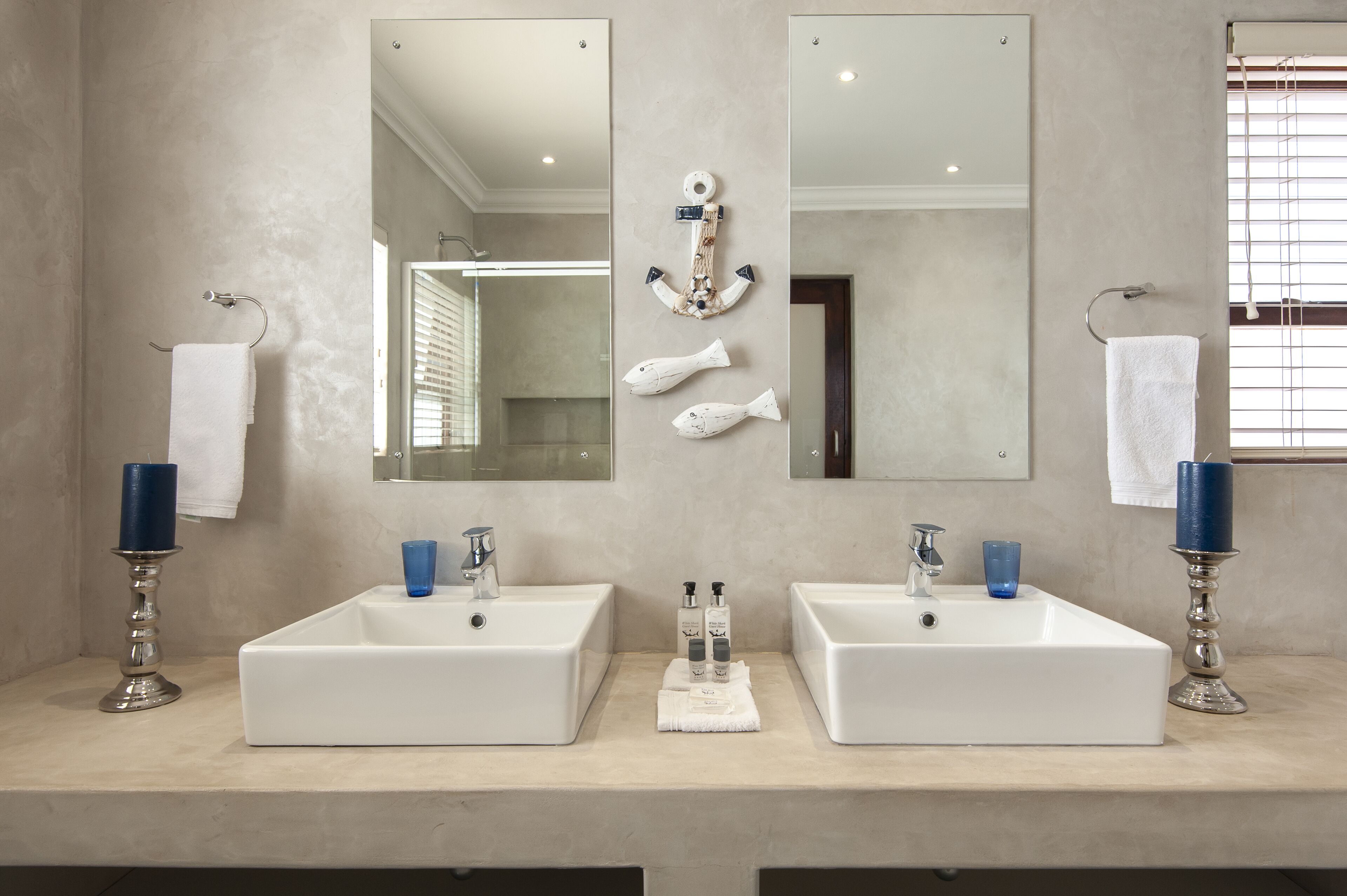 Un baño con dos lavamanos, un espejo grande y un ancla decorativa.