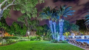 A well-lit outdoor area with a swimming pool, lounge chairs, and palm trees. - Sunsquare Cape Town Gardens (Cape Town)