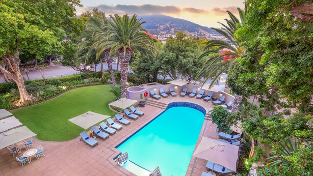 A pool area with a circular seating arrangement, a grassy lawn, and a view of a cityscape in the background. - Sunsquare Cape Town Gardens (Cape Town)