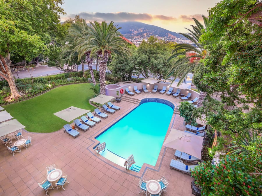 Una piscina al aire libre, sombrillas, sillones reclinables de piscina