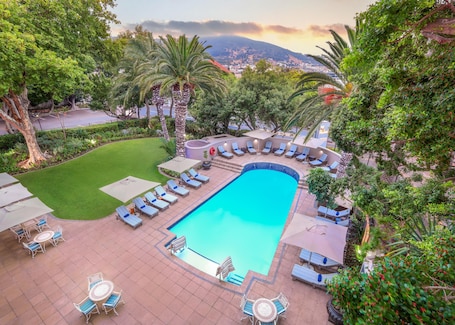 Una piscina al aire libre, sombrillas, sillones reclinables de piscina