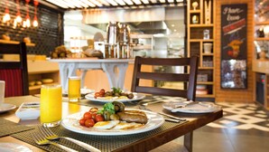A breakfast setting with plates of food, a glass of orange juice, and a dining table. - Sunsquare Cape Town Gardens (Cape Town)