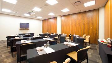 A conference room with multiple tables and chairs, equipped with water bottles and notepads.