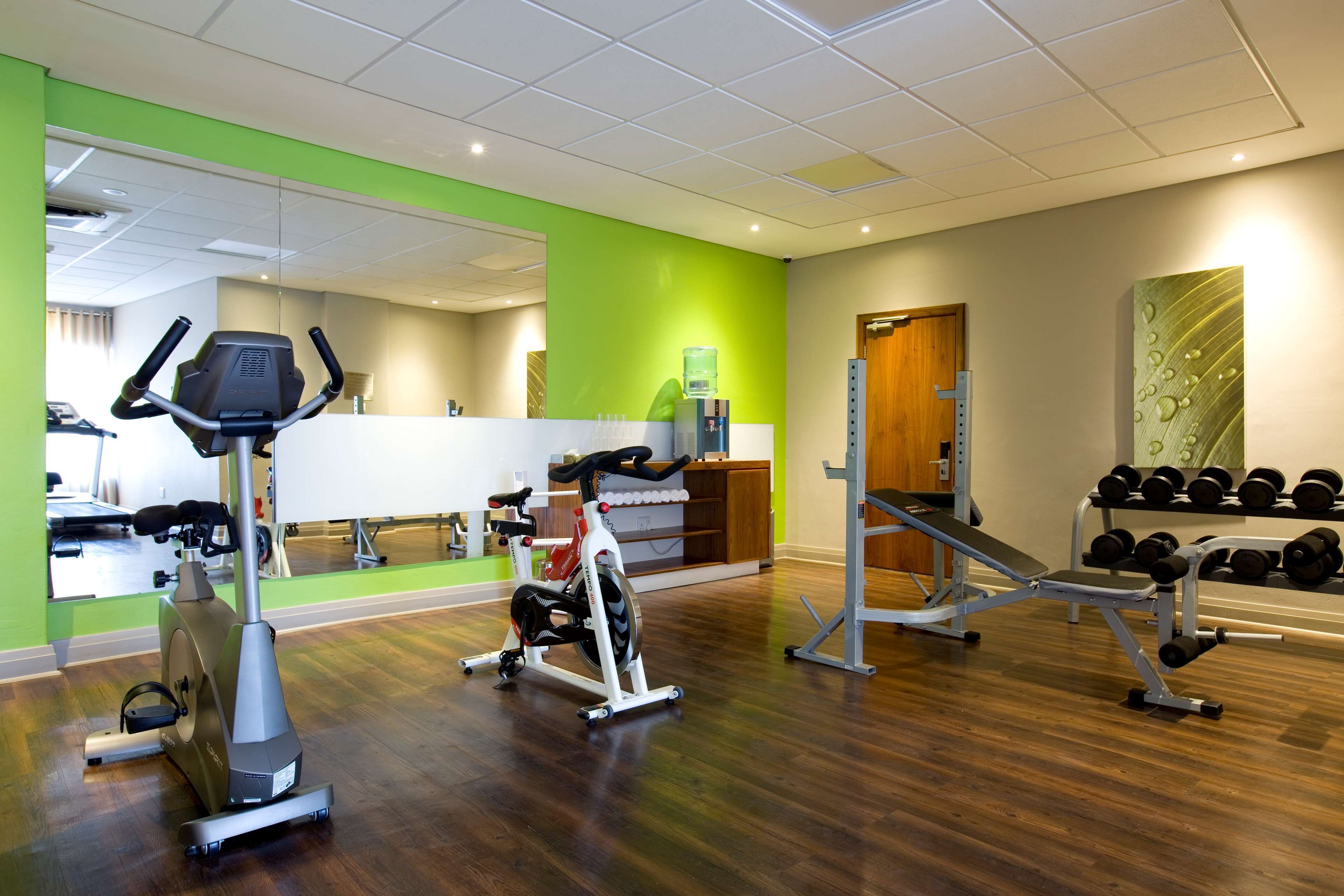 Ein Fitnessraum mit Cardiogeräten, Hantelbänken und Kurzhanteln.