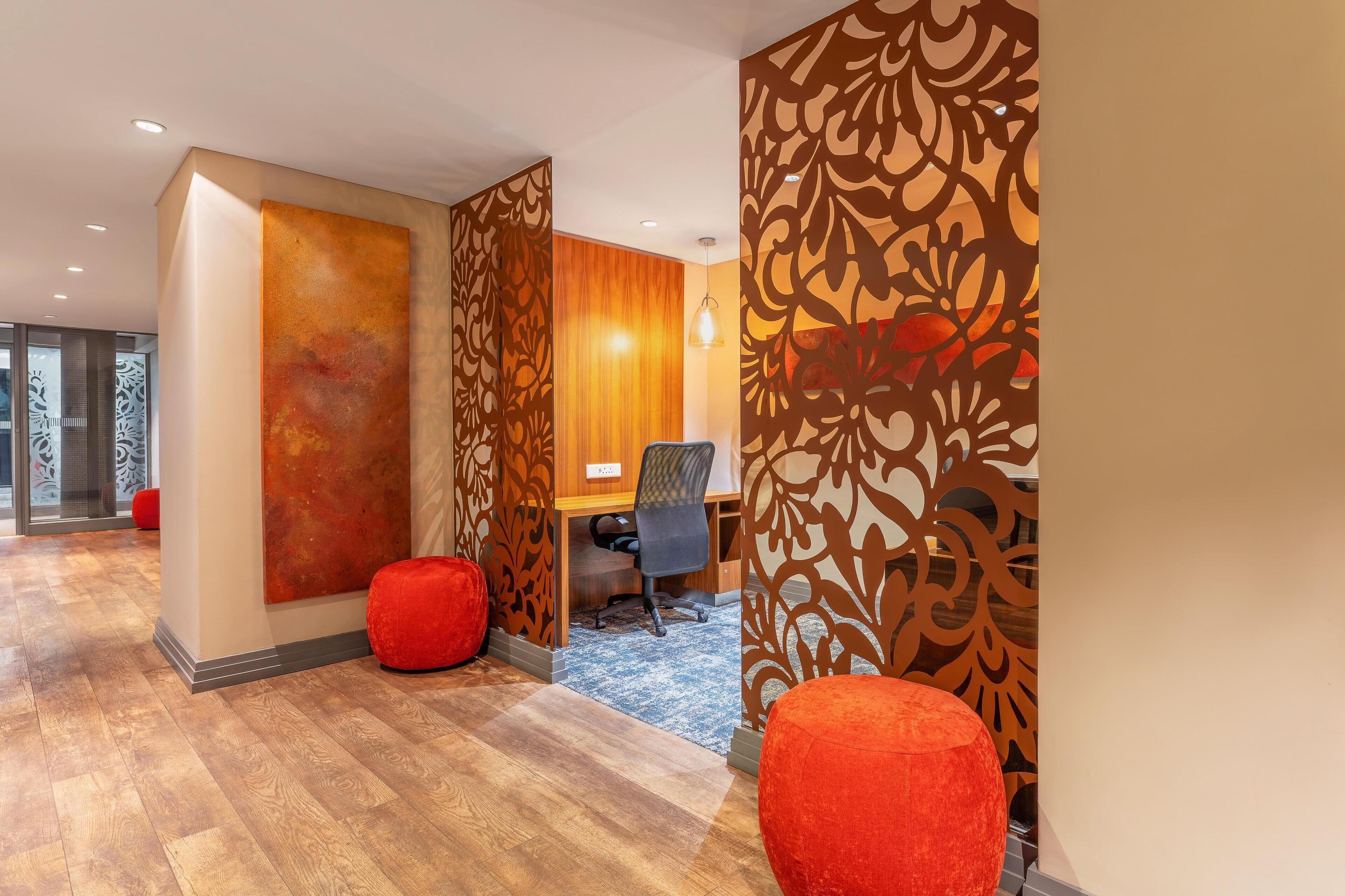 A modern office space with a wooden desk, a computer, and red seating.