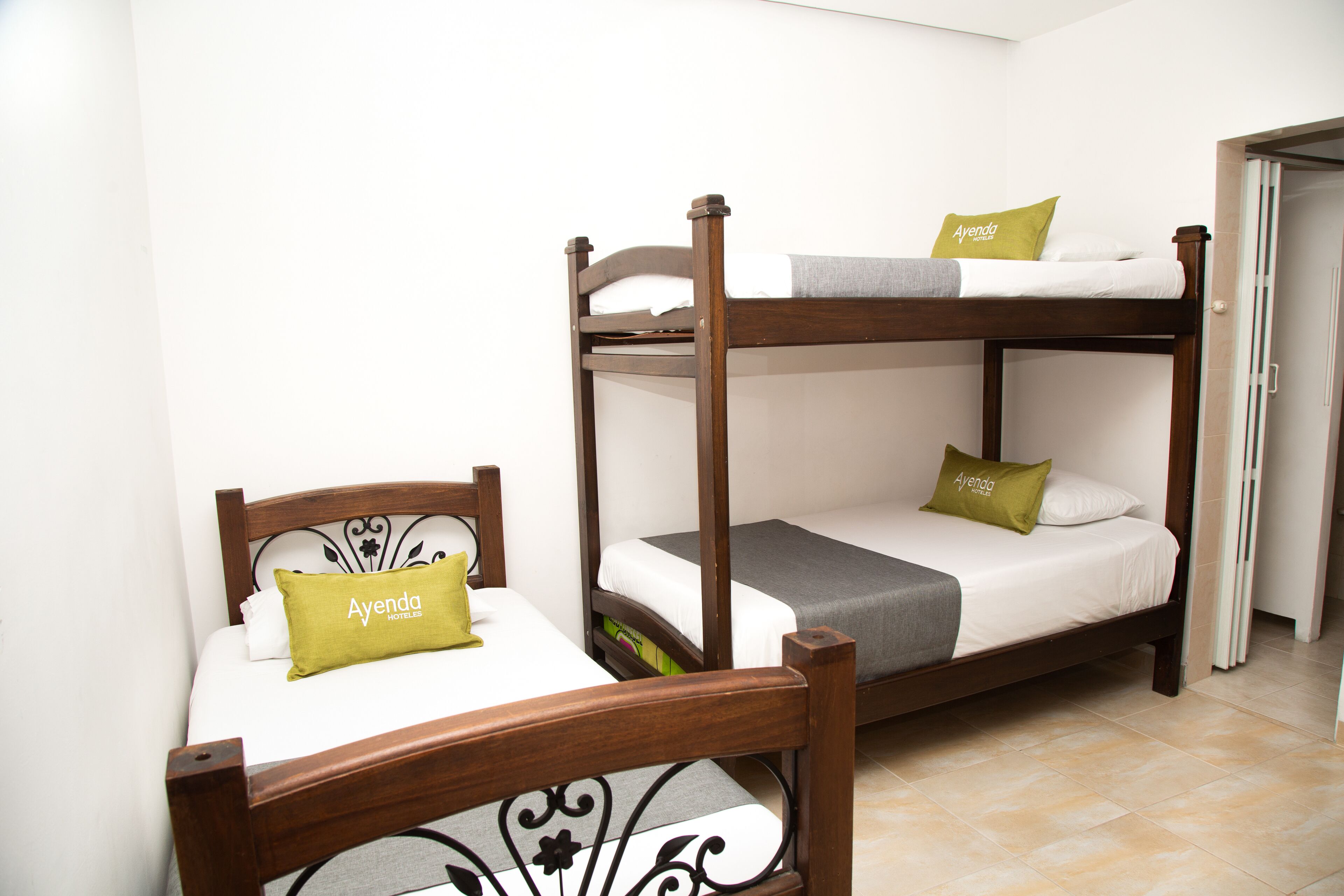 A bunk bed with a wooden frame and two pillows labeled "Ayenda Hotel".