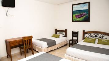 Habitación de hotel con dos camas, un escritorio y una silla. Hay un cuadro en la pared y un televisor de pantalla plana montado sobre el escritorio.