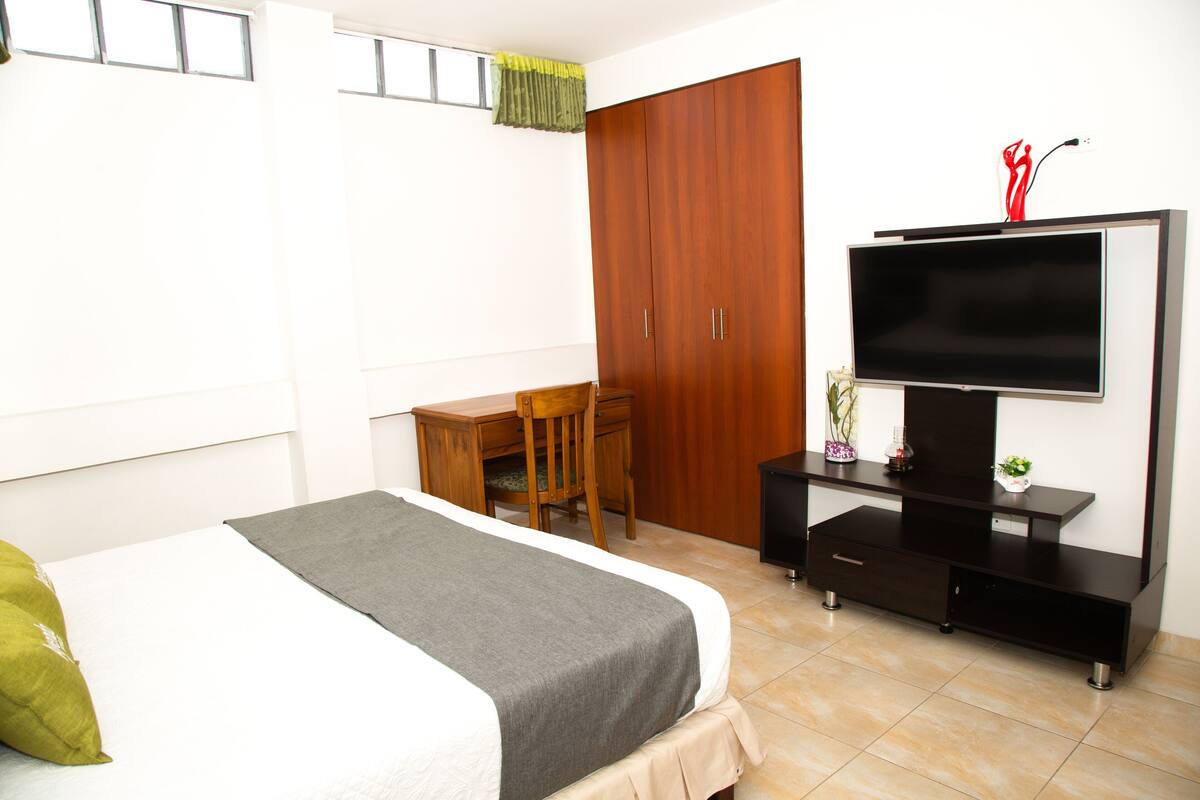 Une chambre d’hôtel équipée d’un lit, d’un bureau, d’une armoire et d’un téléviseur.