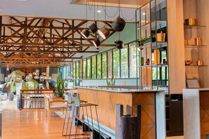 A spacious bar area with wooden flooring, a long counter, and hanging pendant lights. - Termales del Otoño (Villamaria)
